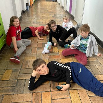 Uczniowie pozują na korytarzu szkolnym w towarzystwie robotów. 